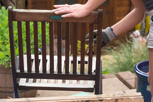 Person streicht Gartenstuhl